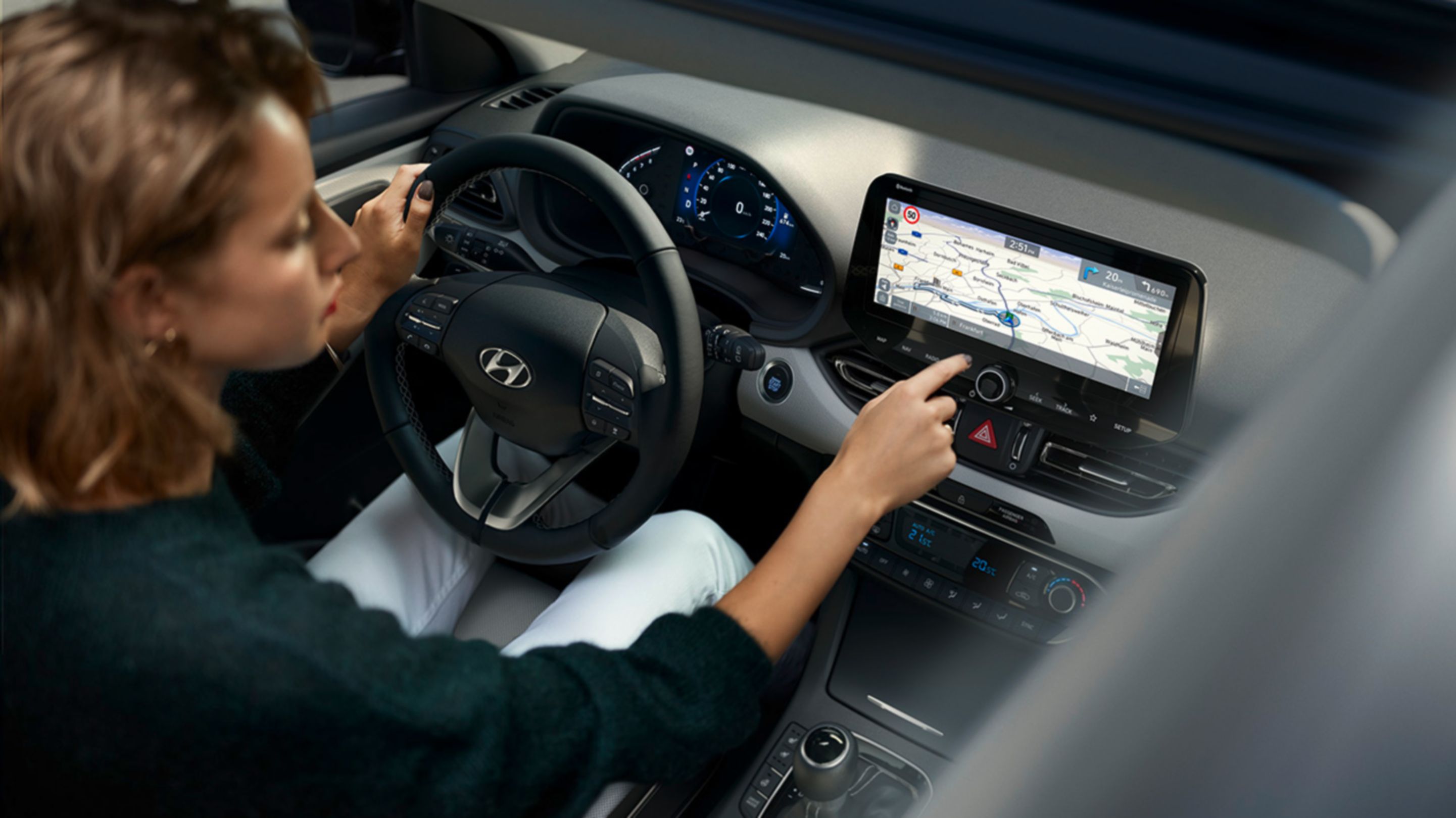 Žena za volantem svého vozu Hyundai i30, používající dotykovou obrazovku.